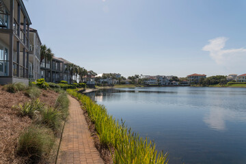 Fototapeta na wymiar Pathway with bricks at the front of single-family homes with Four Prong Lake view at Destin, Florida. There are row of houses on the left with balconies facing the lake on the right.