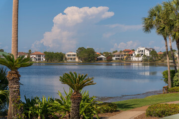 Views of houses across the Four Prong Lake in Destin, Florida. There are plants and palm trees at...