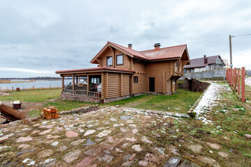 A wooden, log house on the shores of a large lake. Construction in progress