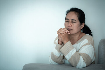 woman kneeling and praying in modern house at sunset time. Female catholic prayer worship to God...