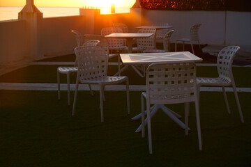 Terrace bar by Black  sea in Batumi, Georgia. hotel Terrace cafe or restaurant with scenic views of sea. white plastic chair and table. golden hour. yellow sunset.