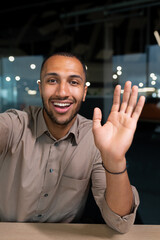 Smiling and cheerful businessman in office taking selfie photo on phone and talking on video call...