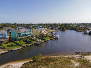 Fototapeta premium Intracoastal waterway at the front of residential buildings at Navarre, Florida. Colorful apartments and family homes with tropical trees and private docks at the front against the clear skyline.