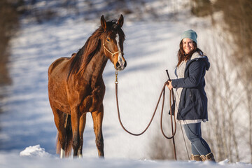 Horsemanship team scene: A young woman and her brown horse interacting and working as a team. Horse...