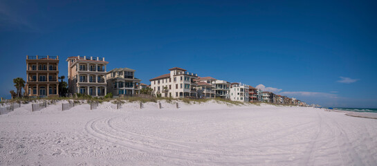 Three-storey beach houses at Destin beach, Florida panorama. Views of white sand with wheel tracks...