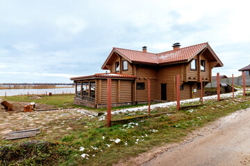 Fototapeta na wymiar A wooden, log house on the shores of a large lake. Construction in progress