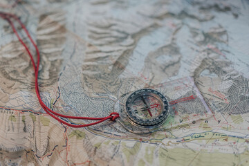 Close up detail of a compass on top of a topographic map. Planning an outdoor adventure.