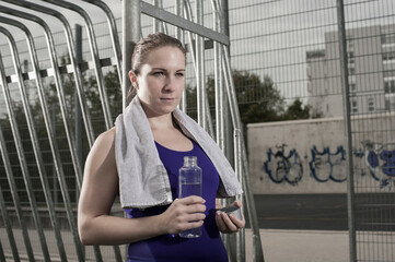 Young woman drinking water on football ground, Bavaria, Germany