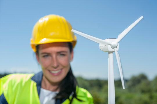 Female engineer with wind turbine at geothermal power station, Bavaria, Germany