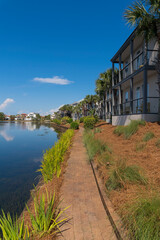 Fototapeta na wymiar Bricks walkway near Four Prong Lake in a neighborhood at Destin, Florida in a vertical shot view. Narrow bricks pavement path along the lake and neighborhood with trees and plants outside.