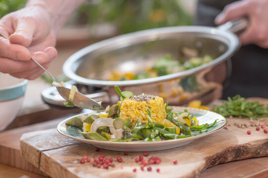 Serving a dish of rice, asparagus, paprika and coriander seeds on plate