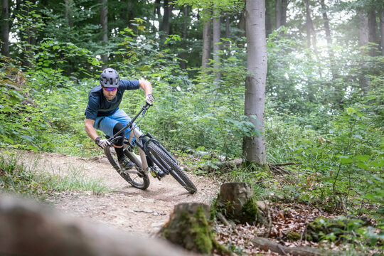 Mountain biker riding down hill on single track in forest, Bavaria, Germany
