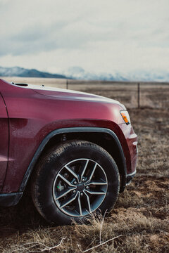A red SUV is pulled off the road next to mountains.