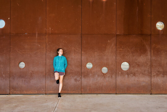 Beautiful jogger leaning on a wall while looking away