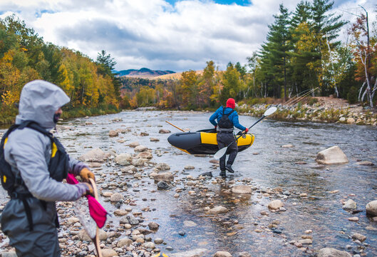 Man and woman walking in river with packrafts and fishing gear