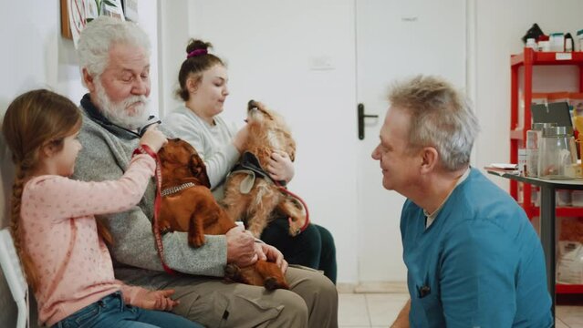Little girl and grandfather with dog in vet waiting room