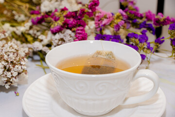 Té caliente en taza blanca y flores de fondo