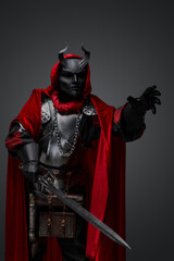 Naklejka premium Shot of dark knight with plate armor and red robe armed with sword.