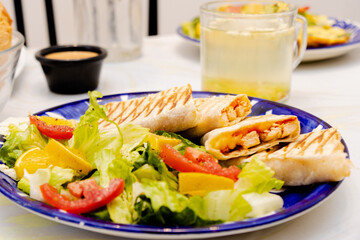 Desayuno saludable, burritas de carne con ensalada fresca a un lado, té de frutas de fondo