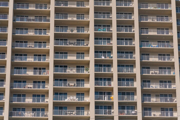 Hotel Apartment building facade with continuous balconies patter in Destin, Florida. Modern multi-storey building exterior with white railings and sliding doors on its balconies.