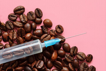 Syringe with coffee beens on pink background - Concept of coffee and health
