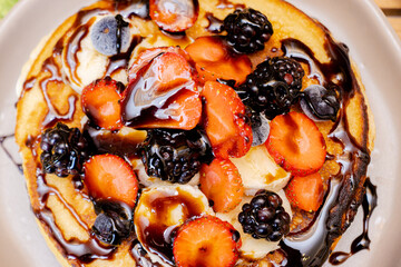 Close-up a hot cakes recién hechos preparados con fruta fresca picada, fresas, zarzamoras y plátano
