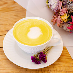 Smoothie amarillo con flores alrededor y corazón de espuma
