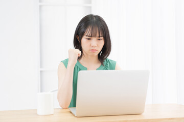 PCを操作しながら怒っている若い女性