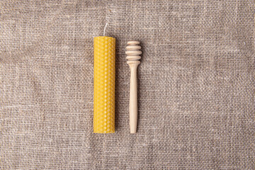 Natural beeswax candle and wooden spoon for honey. Bee products. Space for text