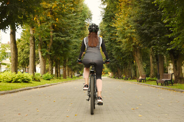 Woman riding bicycle on road outdoors, back view