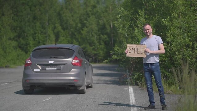 a man catches a passing car, the word Smile is written on the sign. High quality Full HD video recording. slow motion video