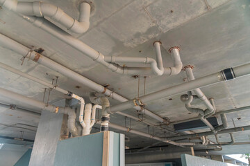 Joint white plastic pipes on the ceiling of a building in Destin, Florida. Building interior with branches of pvc pipes view from below.