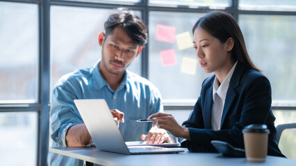 Pointing laptop, Meeting and consulting agenda of indian asia mixed race business man and female china half thai ethnicity bookkeepers discussing balance sheet, stock market profit with yearly tax.