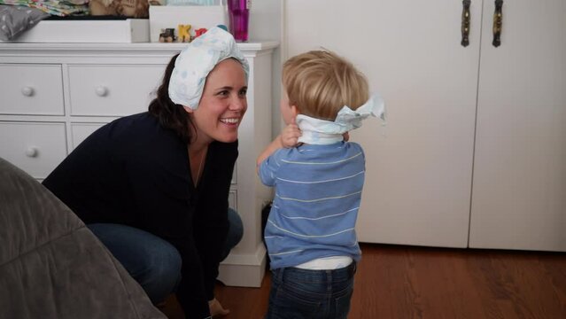 Handheld shot of happy mother and son playing with diapers at home