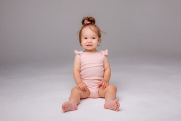 healthy baby girl in a pink bodysuit sits on a white background. space for text