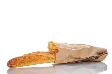 One aromatic baguette in a paper bag, macro isolated on white background.