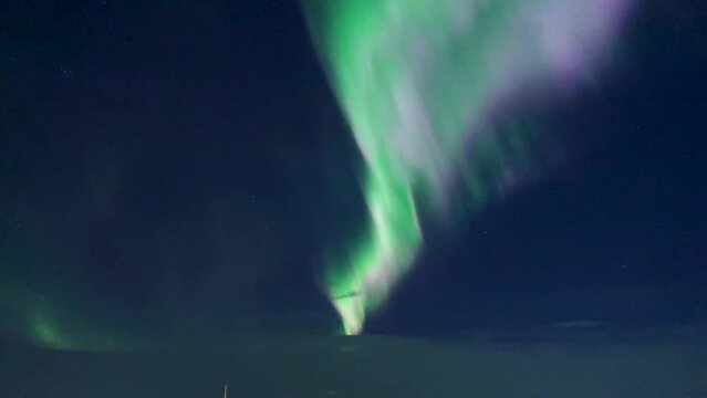 Beautiful green and pink silky dancing specters called polar lights or northern lights - aurora borealis over cold swedish lapland around the Arctic circle caused by solar wind from coronal holes