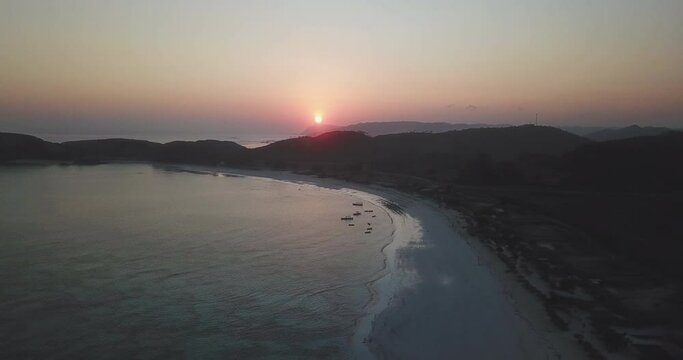 Drone scenic shot of sea by silhouette mountains against sky during sunset