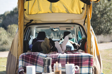 Point of view of the legs of some friends inside a car. Adult female couple enjoying a vacation in a camper van. Life in a van.