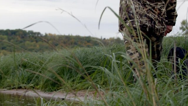 Black Labrador retrieving along the Saint Croix River with hunter.