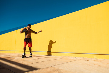 Black man on roller skates riding outside. Urban man posing with roller skates..