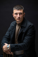 Fototapeta premium Young successful stylish man. Classical portrait of a businessman dressed in a jacket with a watch on his hand.