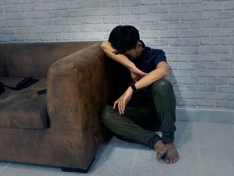 Asian  sad man feeling depression as  lonely near sofa in his room