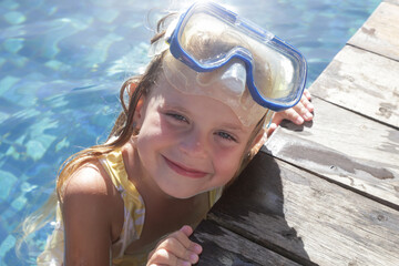 Adorable cheerful 5 years old girl in snorkel mask posing on poolside