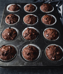 Close up of tin of chocolate zucchini muffins on black background.