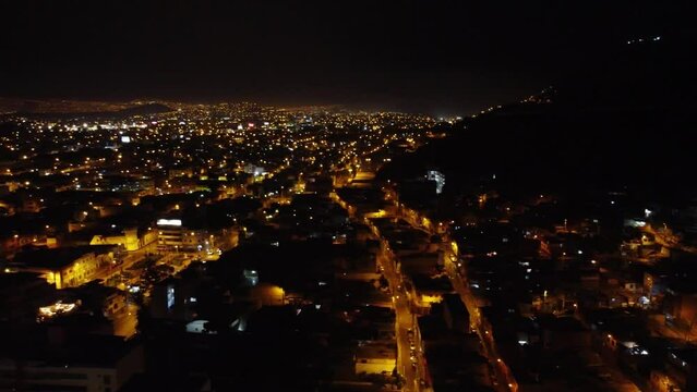 Drone footage of night time city lights, going all the way into the distant horizon. Gimbal camera tilts up while panning left. Recorded in 4k quality in 30 frames per seconds. Located in Lima, Peru.