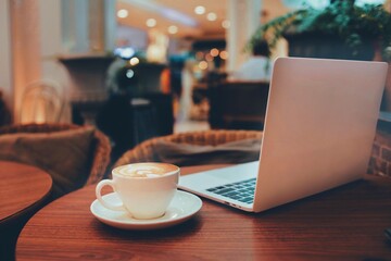 cup of coffee and laptop in coffee shop, vintage filter tone.