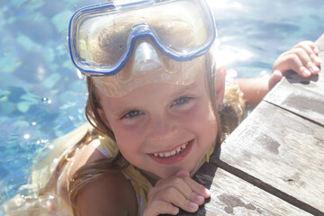 Adorable cheerful 5 years old girl in snorkel mask posing on poolside