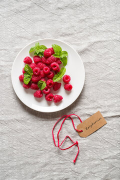 Raspberries fruits and mint leaves on white dish. Top View