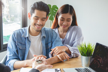 Happy Asian couple receive keys of house from landlord after lease contract approve successful.